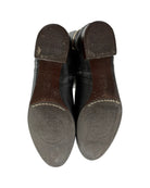 Black leather shoes with visible brand logo on the soles against a white background