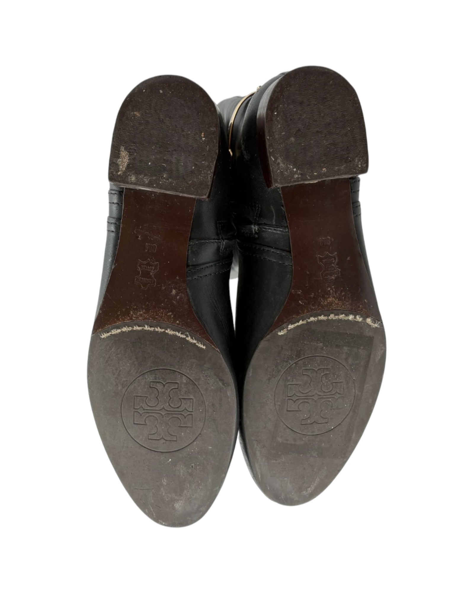 Black leather shoes with visible brand logo on the soles against a white background