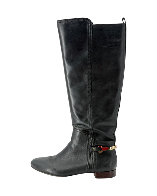Black knee-high boot with a strap on a white background