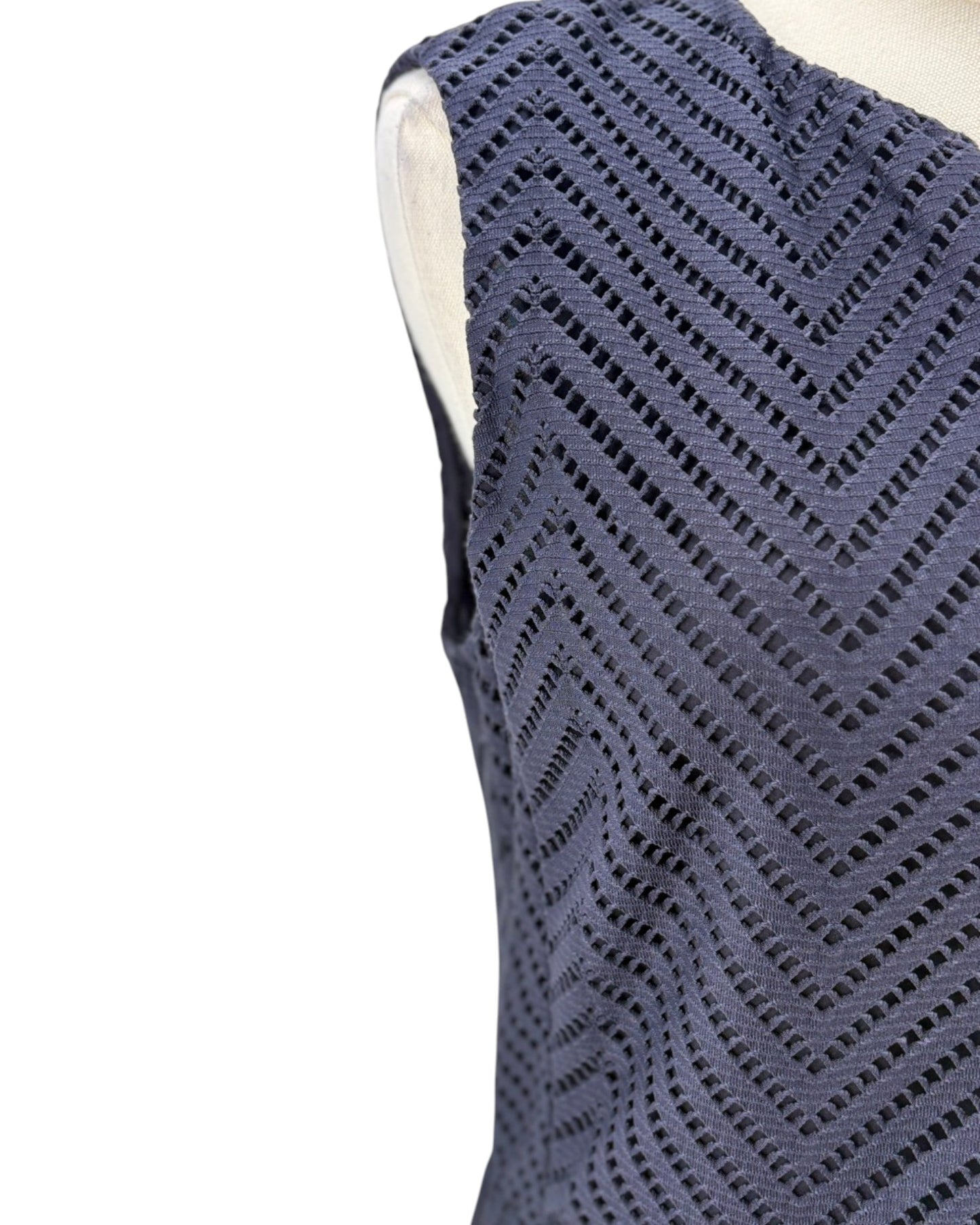 Blue sleeveless knitted top on a mannequin against a white background