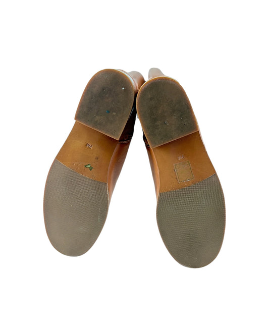 Pair of brown shoes with soles showing wear on a white background