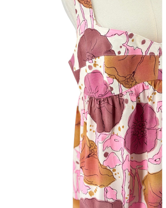 A sleeveless tiered maxi dress with a pink, brown, and orange abstract circle pattern, displayed on a white mannequin torso against a white background.