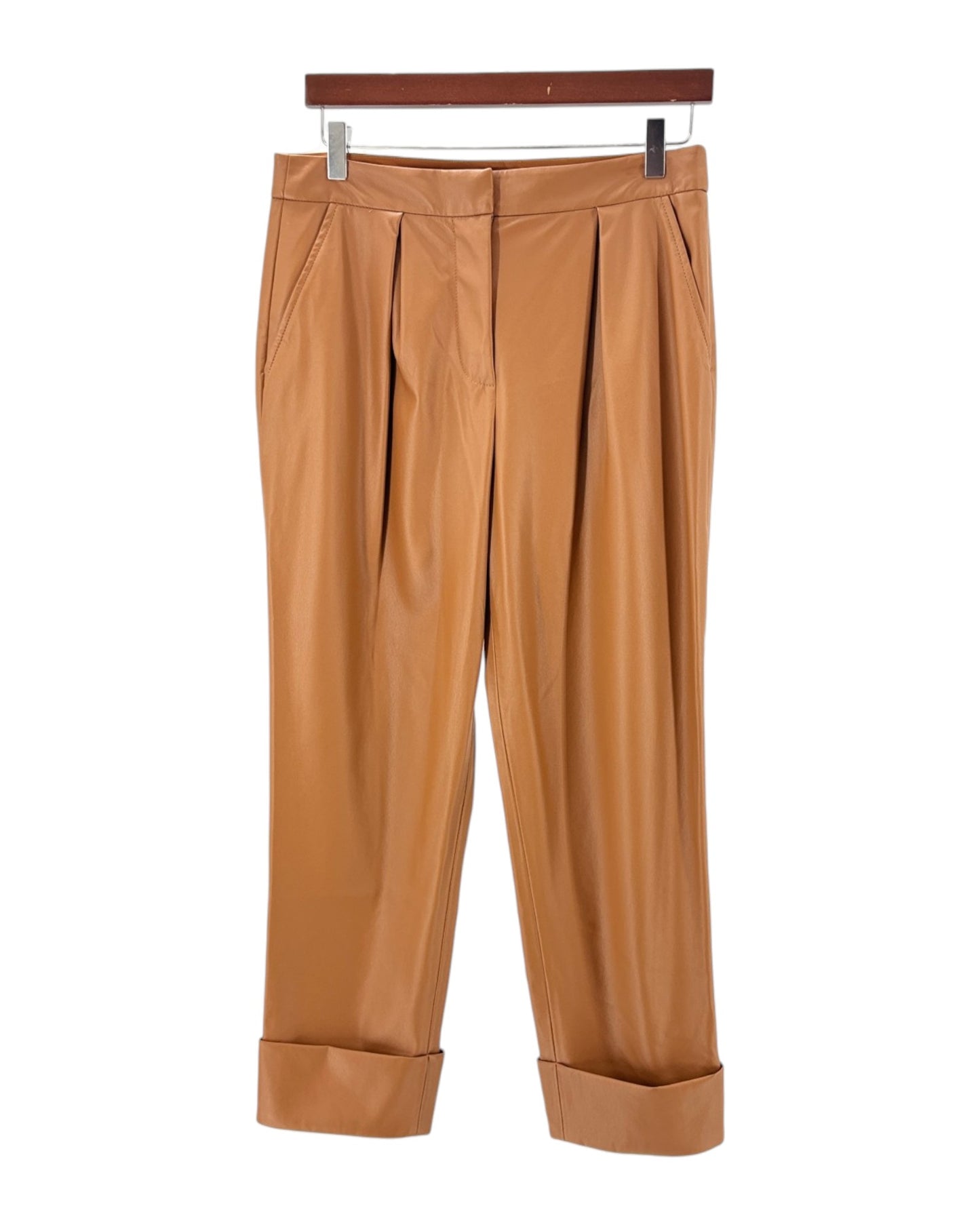 Tan pleated pants on a hanger against a white background