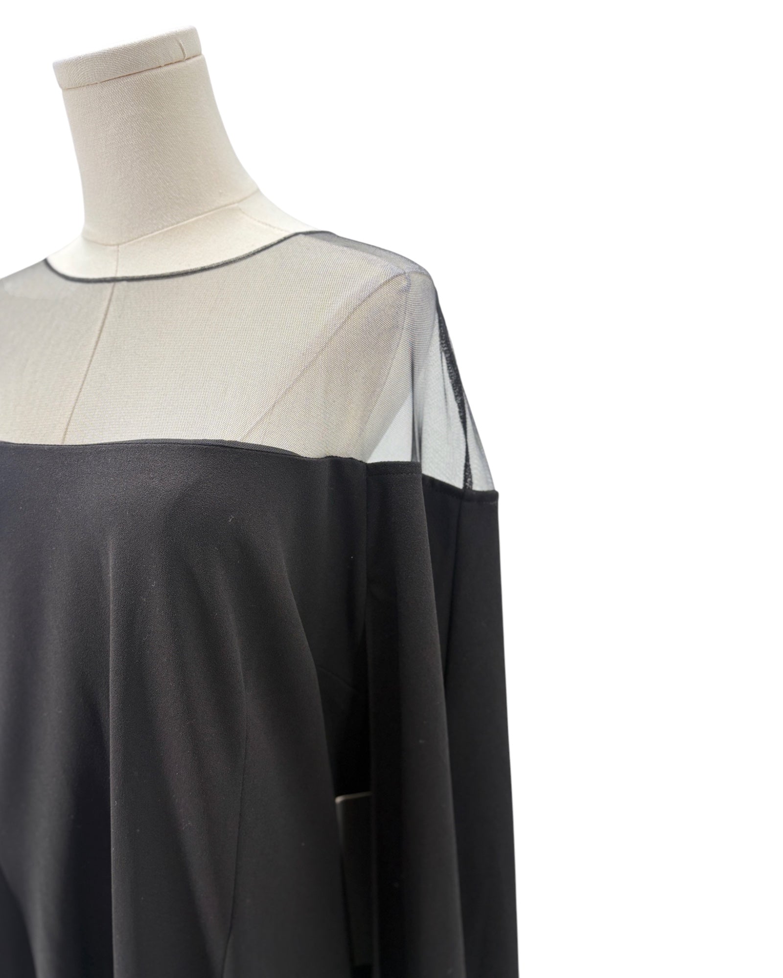 Black and sheer dress on a mannequin against a white background