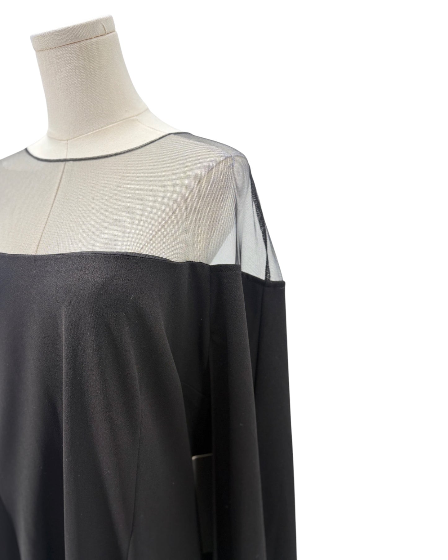 Black and sheer dress on a mannequin against a white background