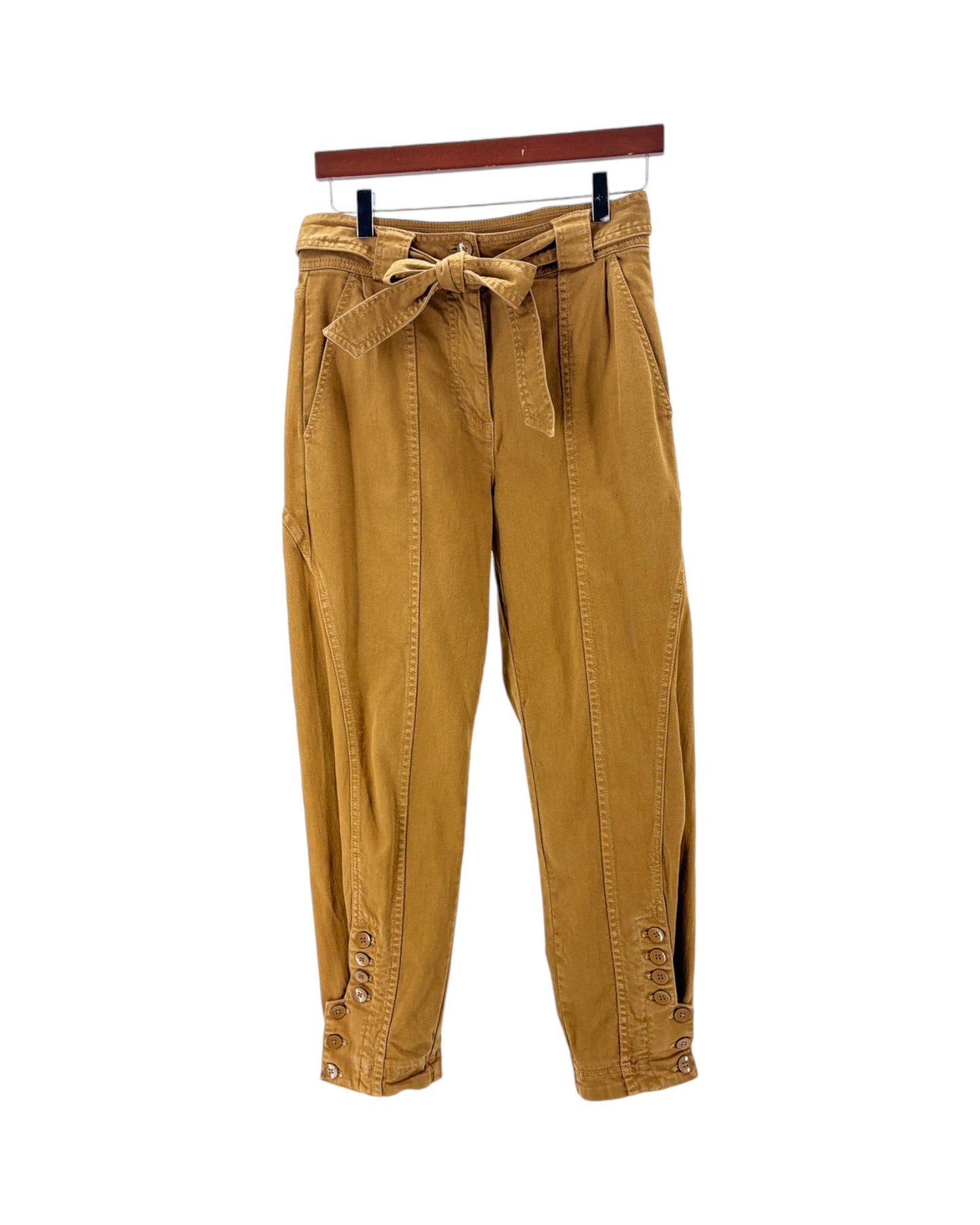 A pair of mustard yellow corduroy pants with a matching waist tie belt, hanging from a wooden hanger against a plain white background.