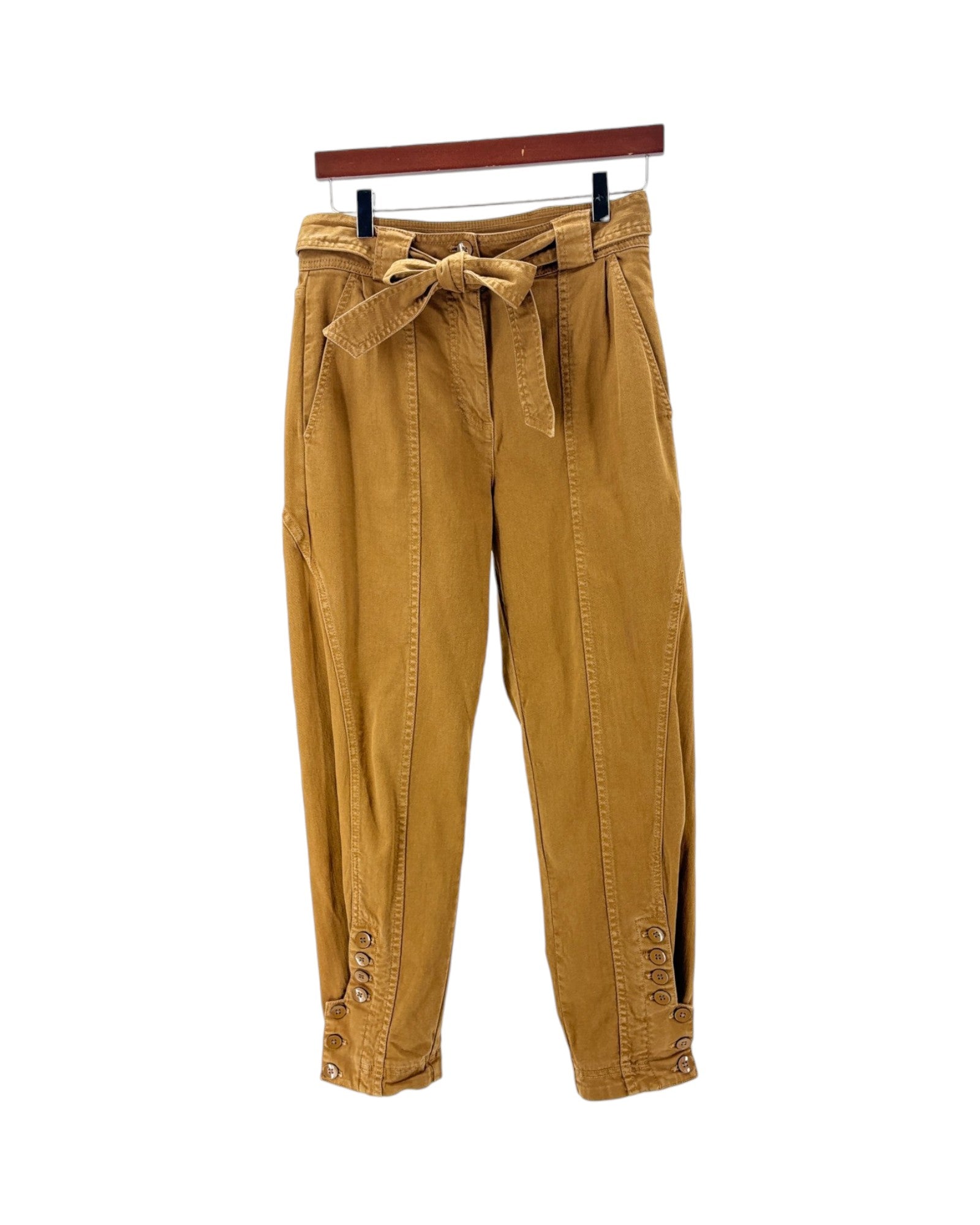 A pair of mustard yellow corduroy pants with a matching waist tie belt, hanging from a wooden hanger against a plain white background.
