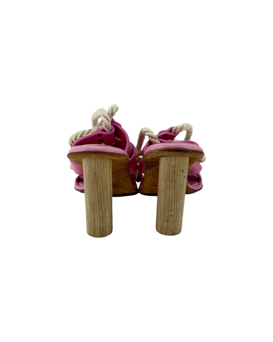 A pair of pink leather sandals featuring thick beige rope details woven through the straps and gold-tone metal studs, shown against a plain white background.