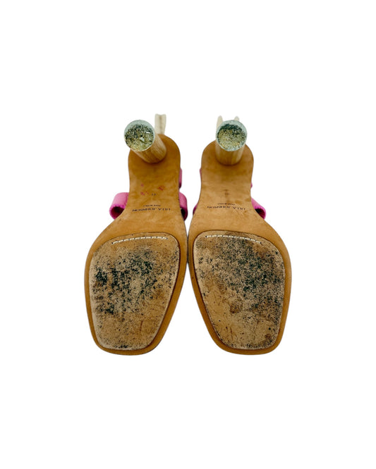 A pair of women's high-heeled sandals shown from the sole, featuring tan leather soles with heavy scuffing and dirt, pink straps, and clear round heel caps.