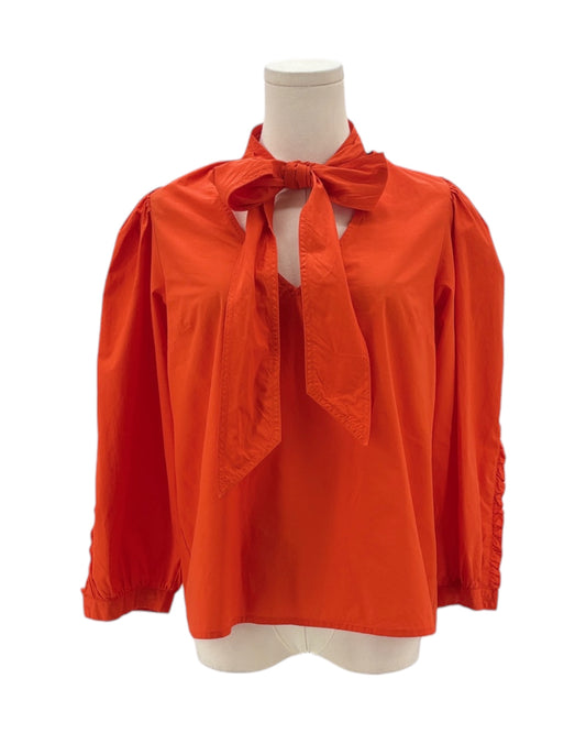 Orange blouse with a bow tie on a mannequin against a white background