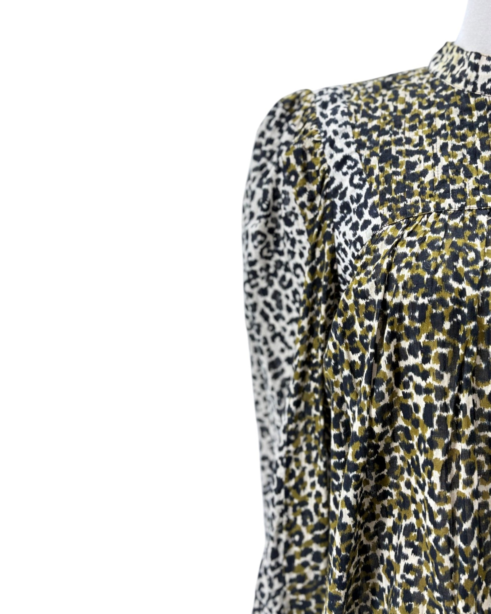 Close-up of a leopard-print blouse on a mannequin, showing a smocked chest panel and long puffed sleeves against a plain white background.