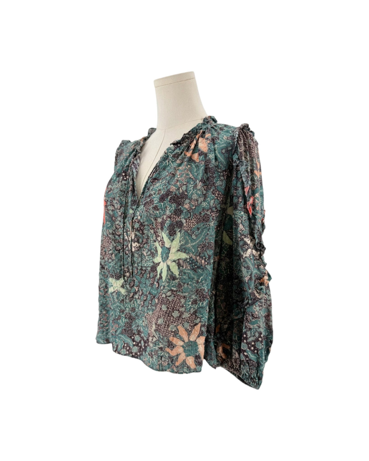 Multi color geometric floral print, full length sleeves with cascade sleeves finished with elastic cuff, v-neckline with tassel detail on a mannequin on a white background