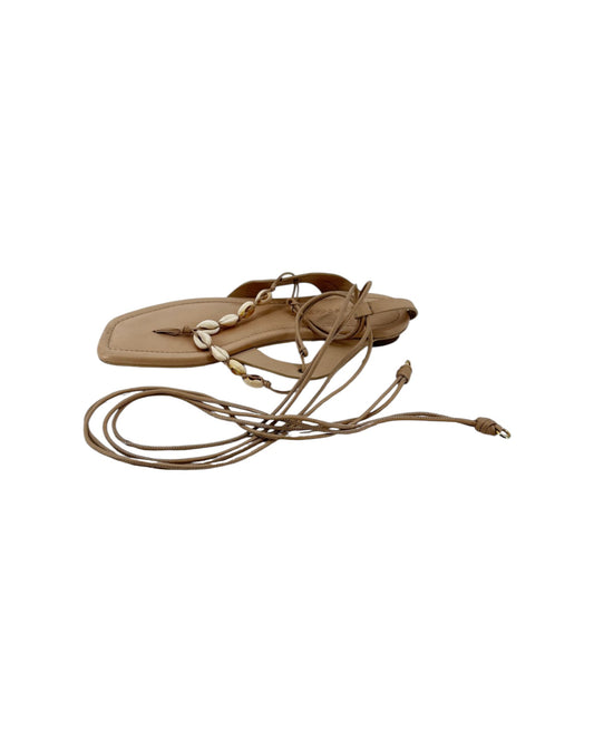 Leather thong sandal with long leather ankle wrap straps and seashell details on a white background