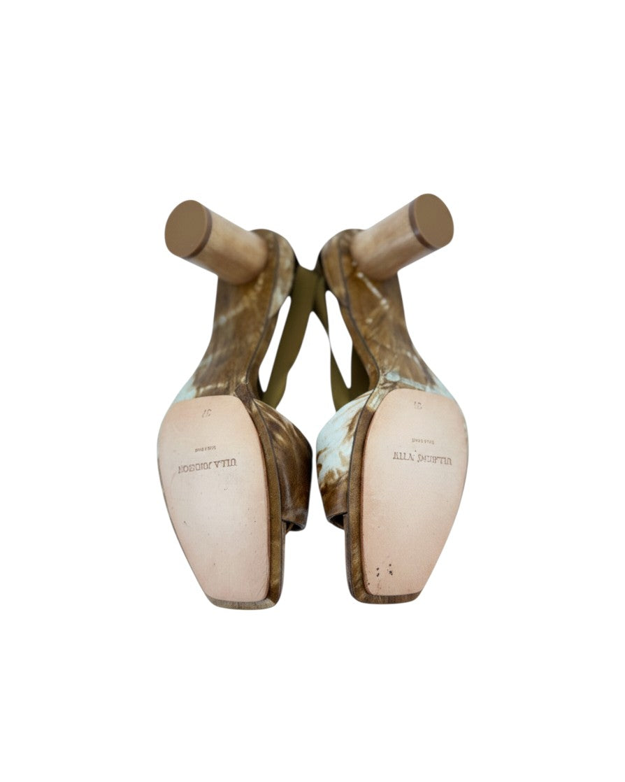Brown and white heels with a gold ring at the toe strap heels and satin ribbon laces on a white background with leather soles that say Ulla Johnson