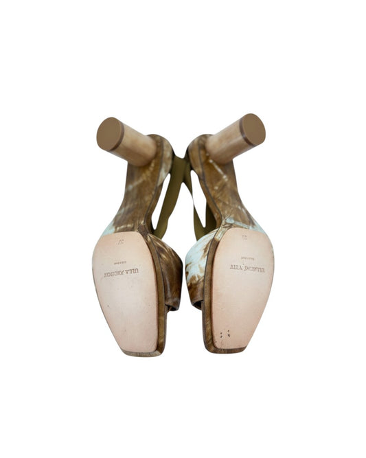 Brown and white heels with a gold ring at the toe strap heels and satin ribbon laces on a white background with leather soles that say Ulla Johnson