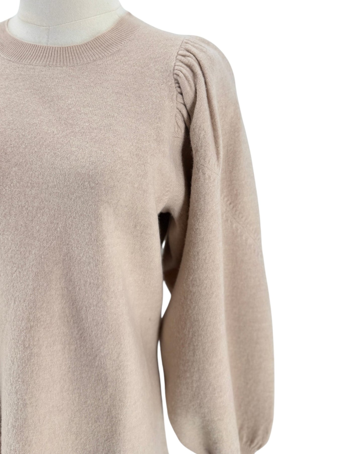 A close-up of a light beige knit sweater dress on a mannequin, showing a crew neck and a long puff sleeve with gathered detailing.