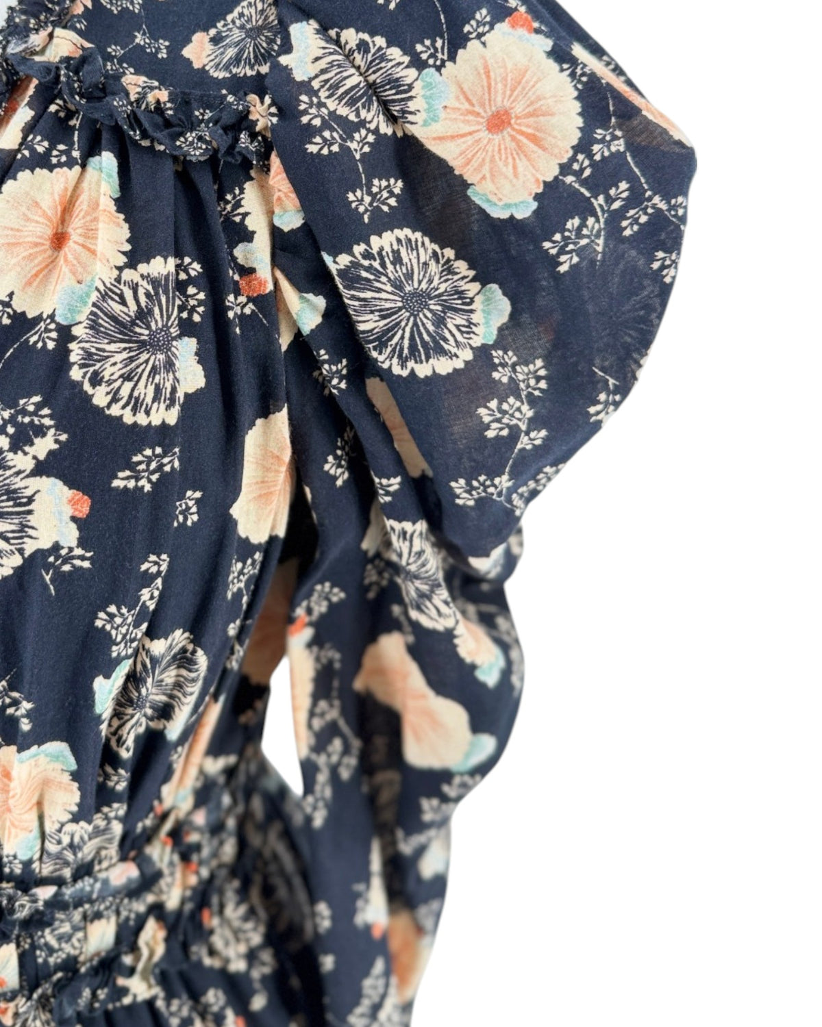 A close up picture of a black long-sleeve mini dress with a beige and peach floral pattern, displayed on a cream mannequin torso against a plain white background.
