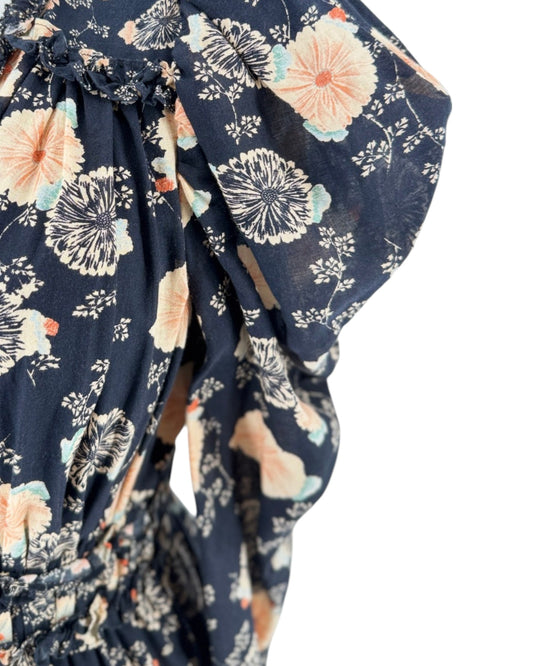 A close up picture of a black long-sleeve mini dress with a beige and peach floral pattern, displayed on a cream mannequin torso against a plain white background.