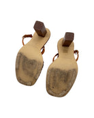 Pair of sandals with tan soles on a white background