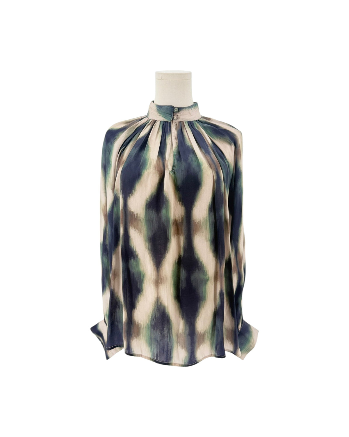 A long-sleeve high-neck blouse with a geometric ikat pattern in navy blue, olive green, and cream, displayed on a mannequin torso against a white background.