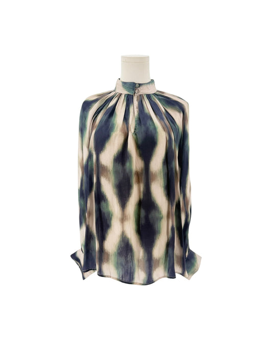 A long-sleeve high-neck blouse with a geometric ikat pattern in navy blue, olive green, and cream, displayed on a mannequin torso against a white background.