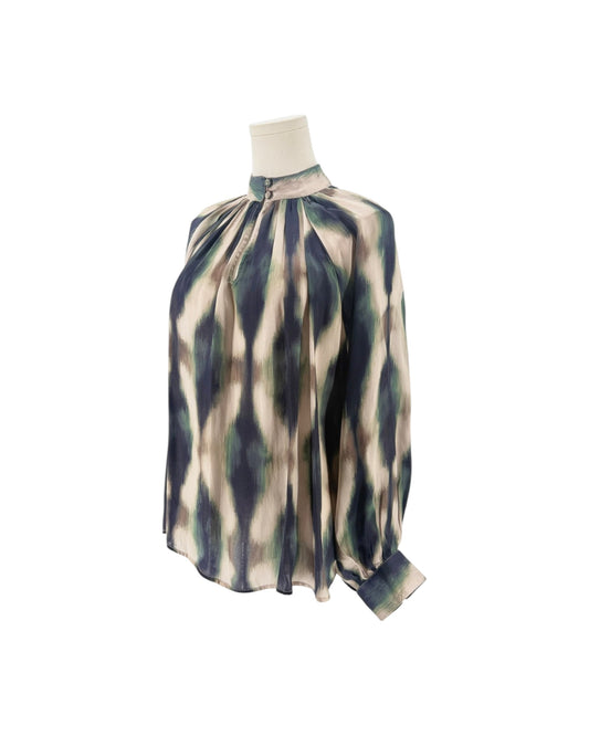 A close-up of a high-neck blouse displayed on a mannequin, featuring a pleated gathered bodice and a long sleeve. The fabric has an abstract, painterly pattern in beige, navy blue, and sage green.