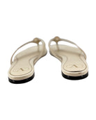 Pair of cream flip-flops with black soles on a white background