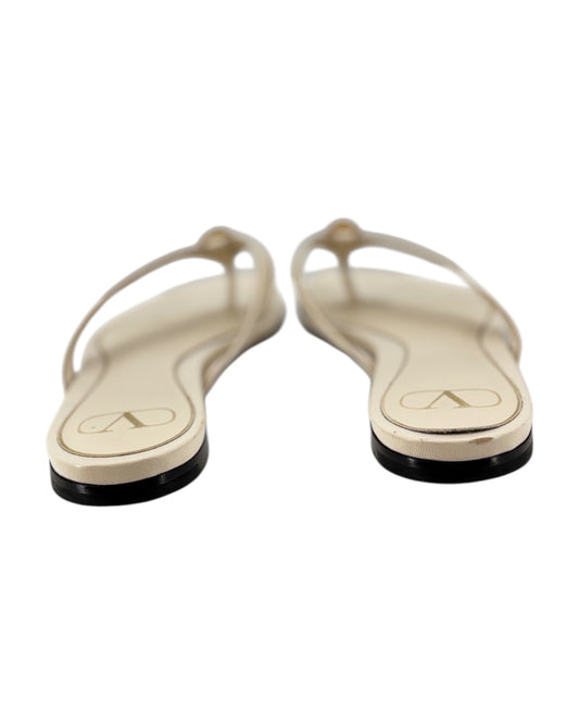 Pair of cream flip-flops with black soles on a white background