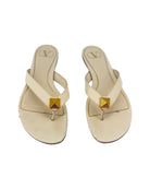 Pair of cream sandals with gold square accents on a white background