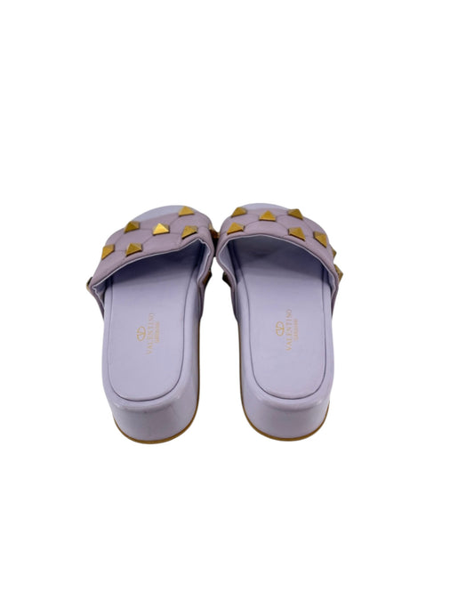 A pair of lavender-purple wedge slide sandals with gold pyramid studs, shown from a top-down view on a white background.