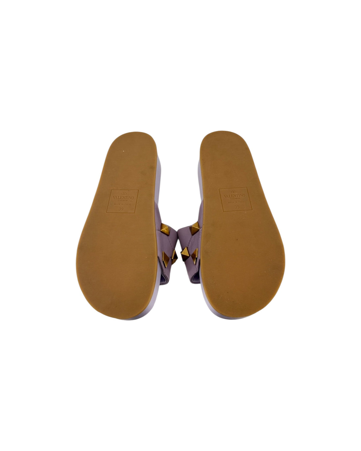 A pair of flat sandals shown from a top-down view, featuring purple woven straps with gold-tone studs and a tan outsole.