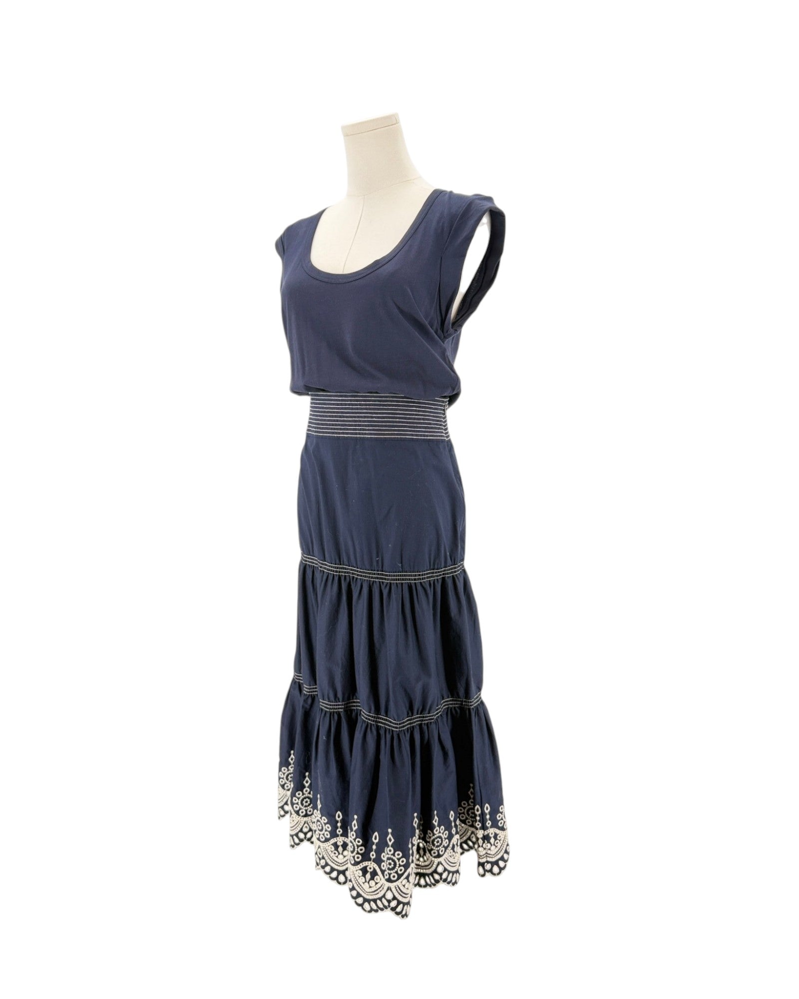 Navy sleeveless midi dress with delicate trim along the hem, scoop neck, side zip and hook. On a mannequin on a white background.