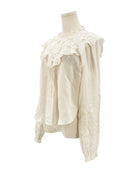 White lace blouse on a mannequin against a white background
