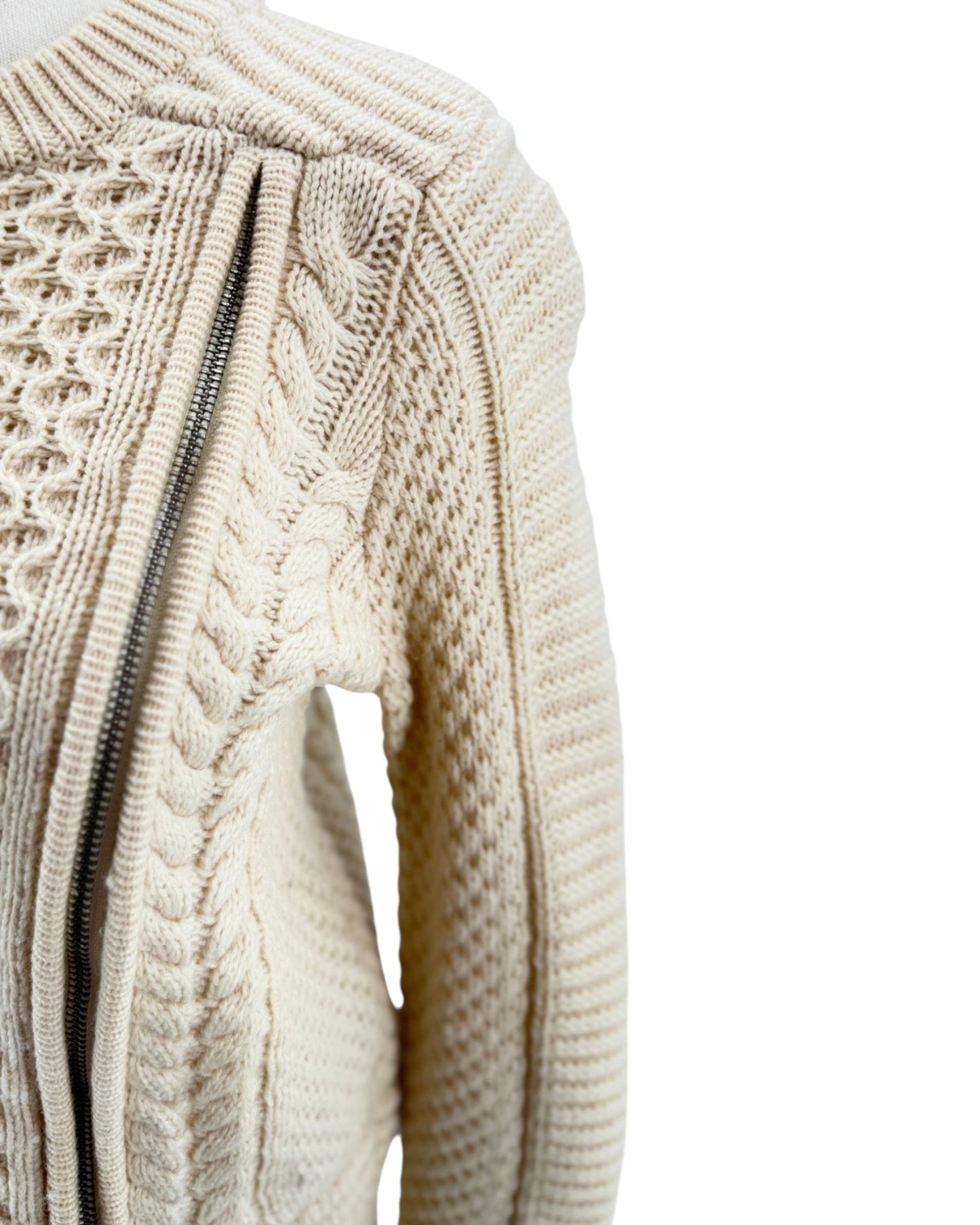 Close-up of a cream-colored knitted sweater with cable pattern on a white background