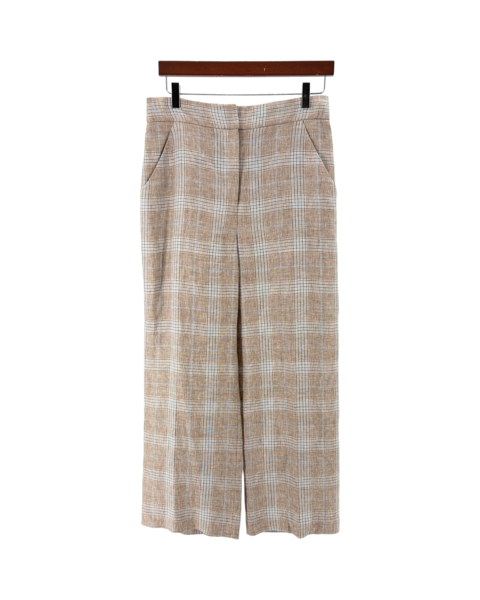 A pair of beige and white plaid cropped trousers hanging from a wooden hanger against a plain white background.