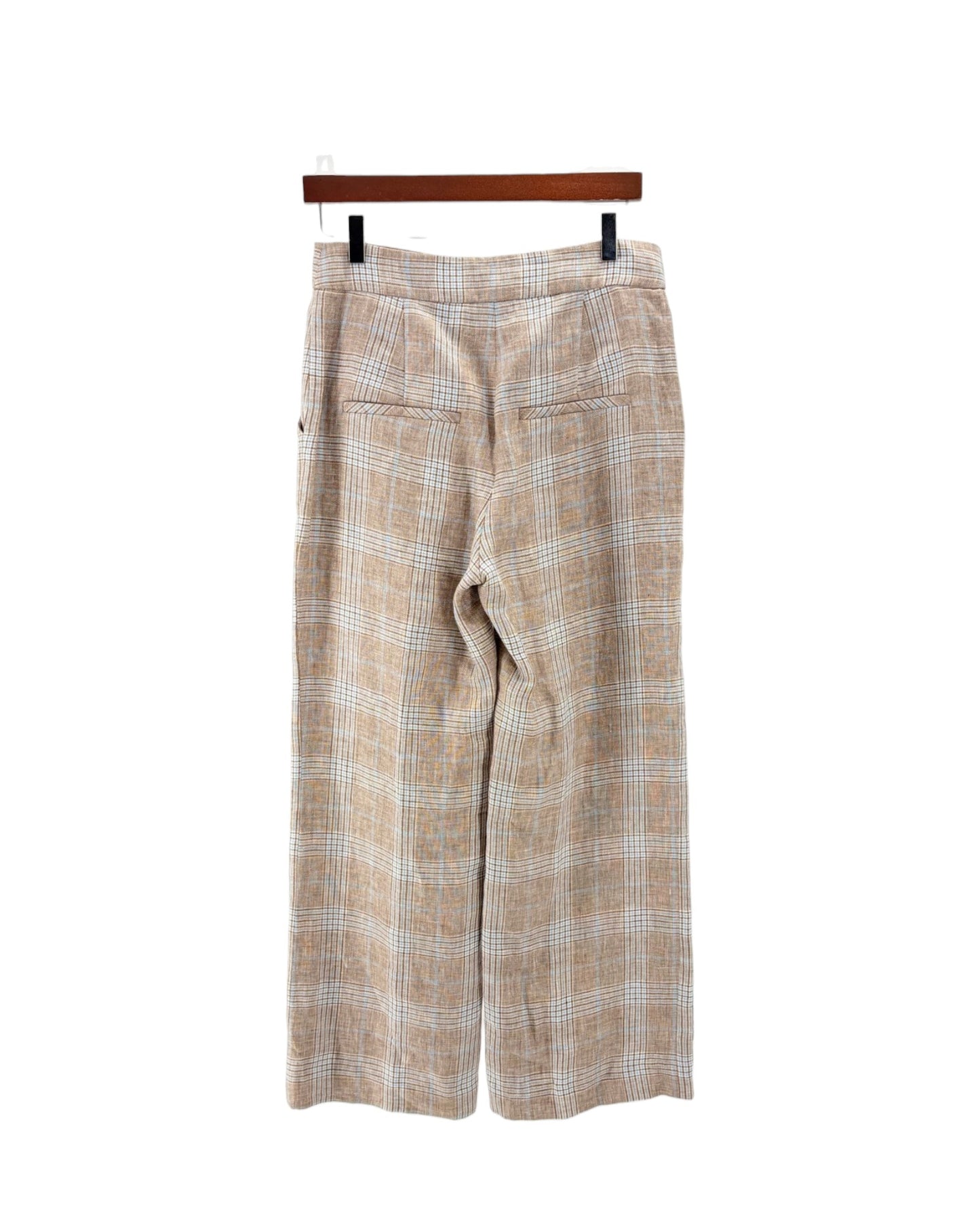 A pair of wide-leg cropped trousers in a beige and white plaid pattern, hanging from a wooden hanger against a plain white background.