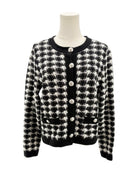 Black and white houndstooth patterned cardigan on a mannequin against a white background