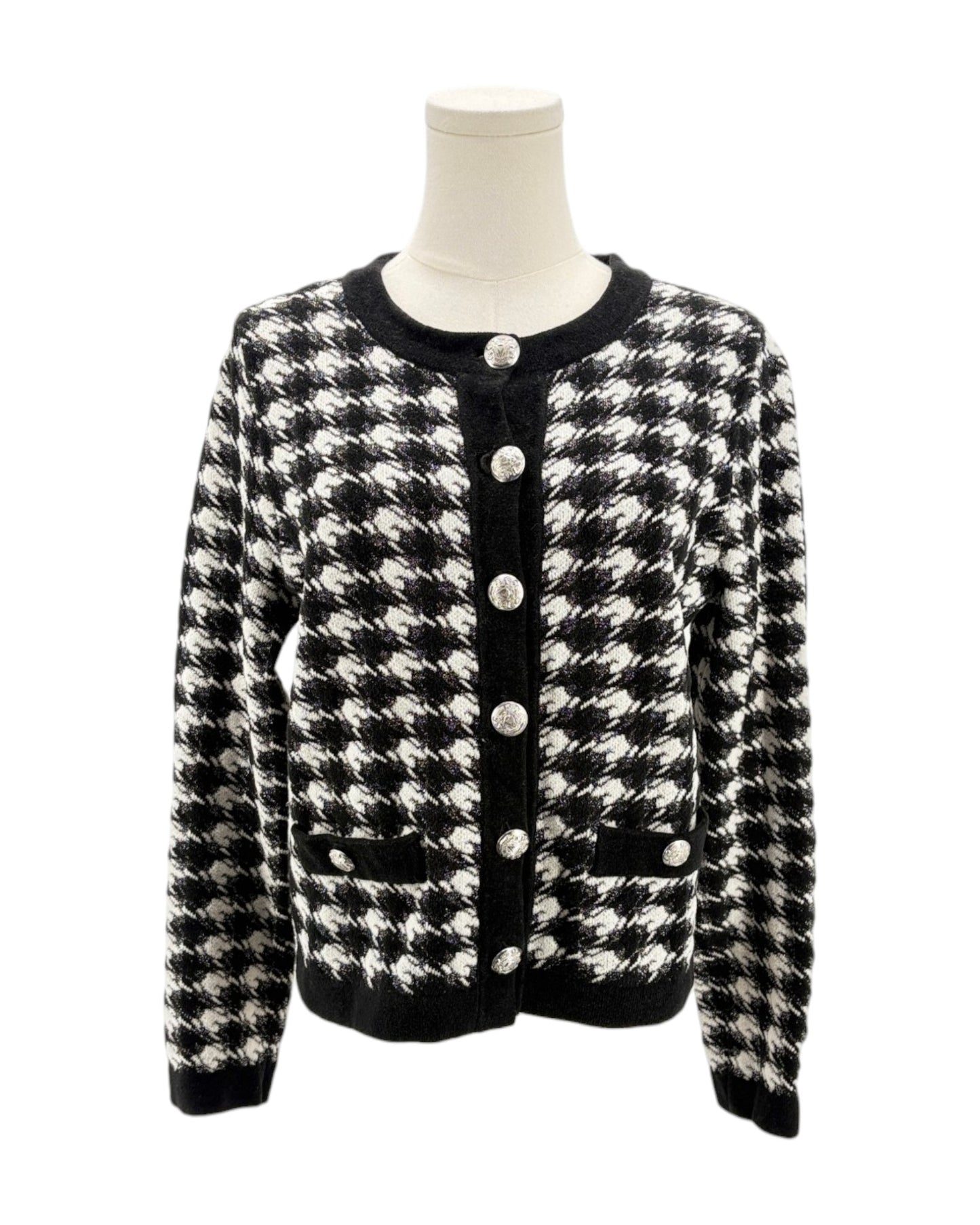 Black and white houndstooth patterned cardigan on a mannequin against a white background