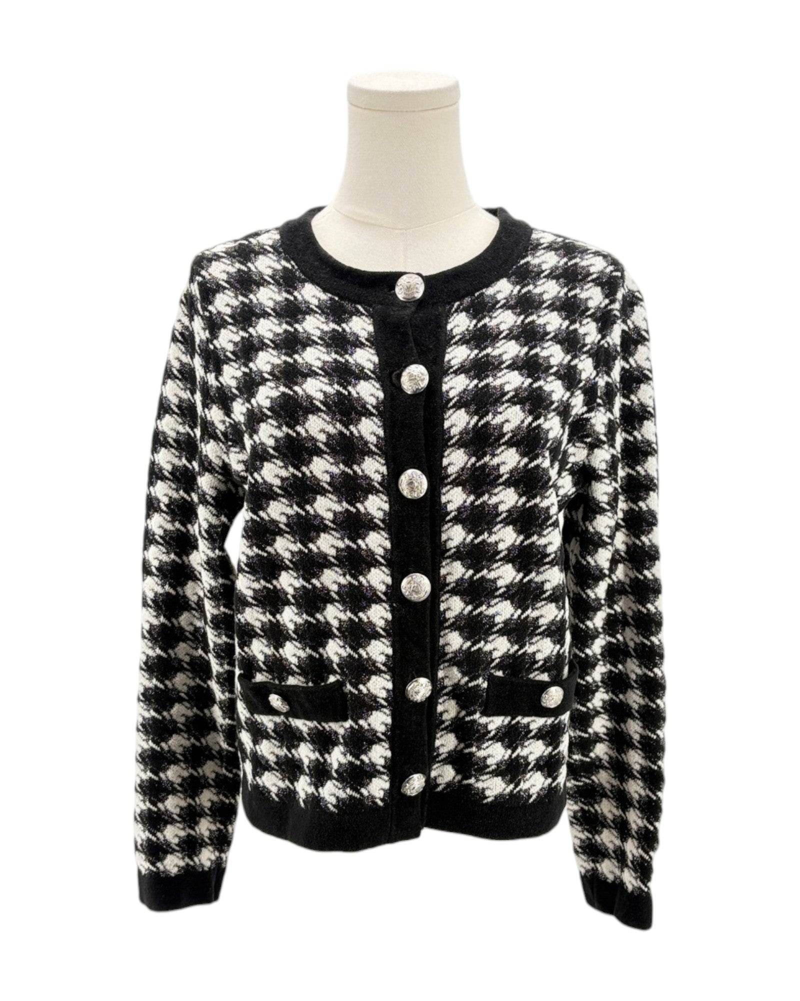 Black and white houndstooth patterned cardigan on a mannequin against a white background