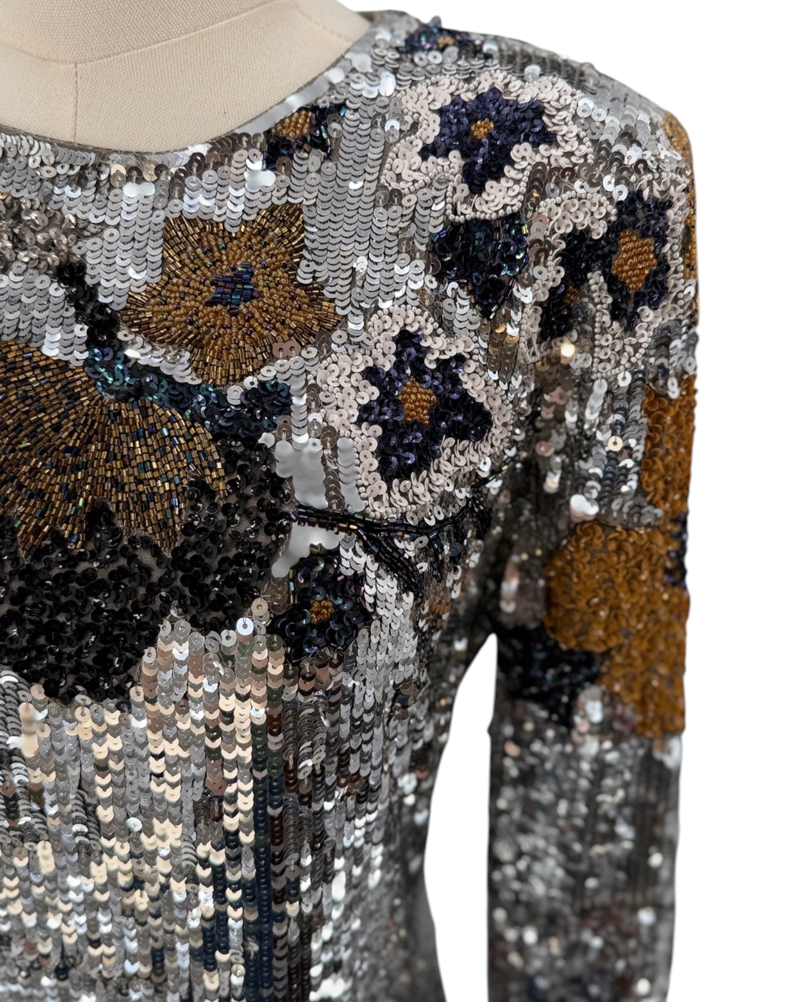 Close-up of a sequined garment with floral patterns on a mannequin.