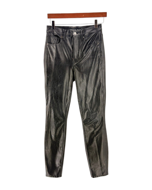 Black leather pants on a hanger against a white background