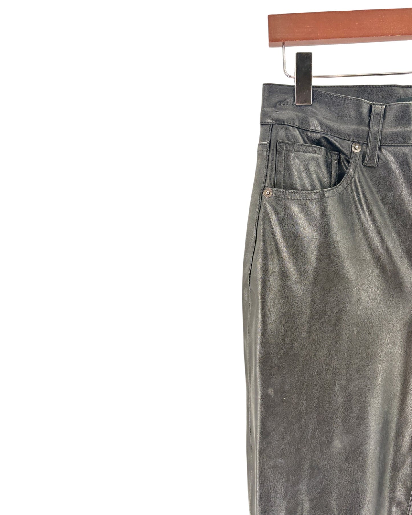 black pants hanging on a wooden rod against a white background