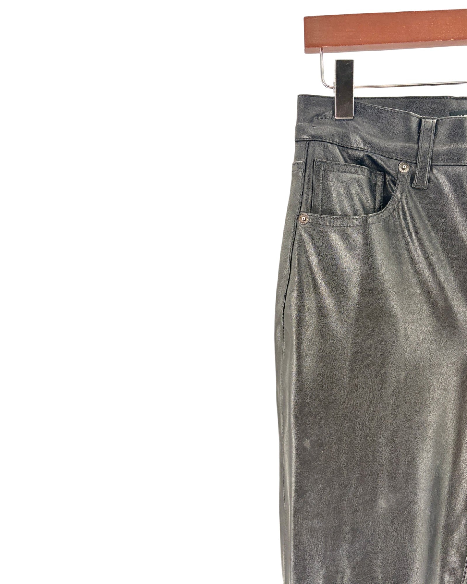black pants hanging on a wooden rod against a white background