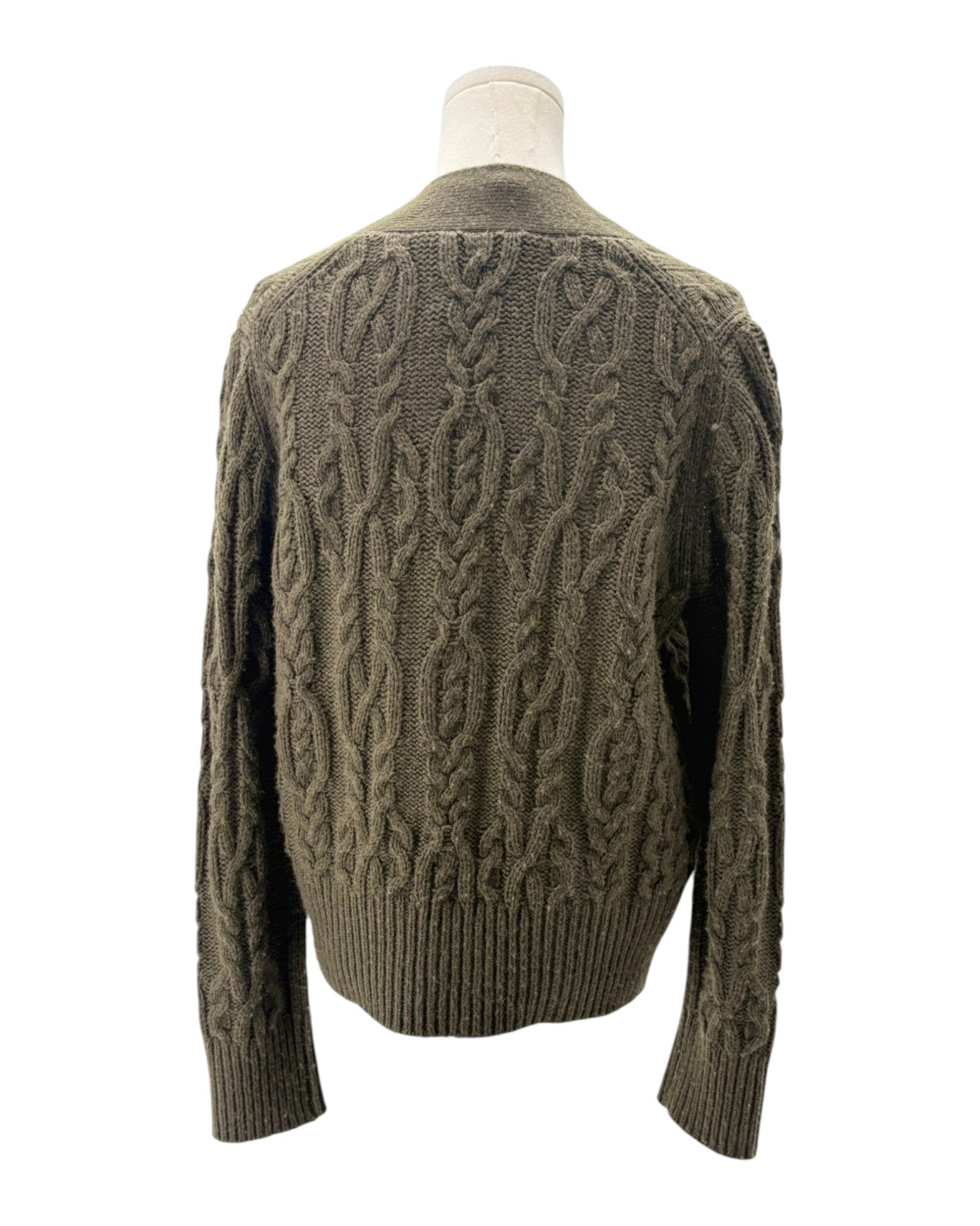 Green cable knit sweater on a mannequin against a white background