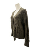 Green cable knit cardigan on a mannequin against a white background