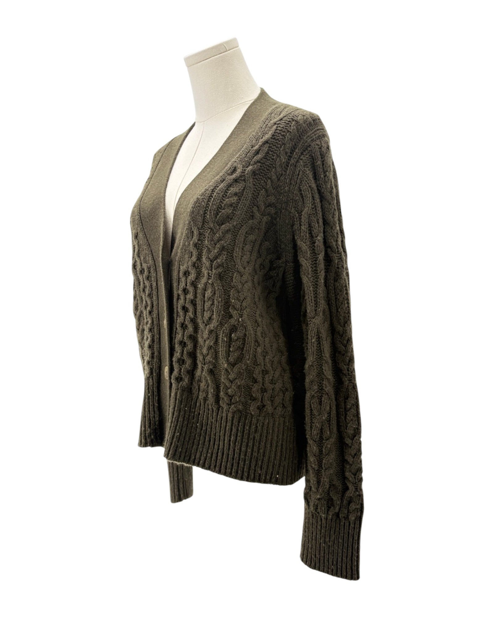 Green cable knit cardigan on a mannequin against a white background