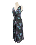 Black pleated dress with floral pattern on a mannequin against a white background