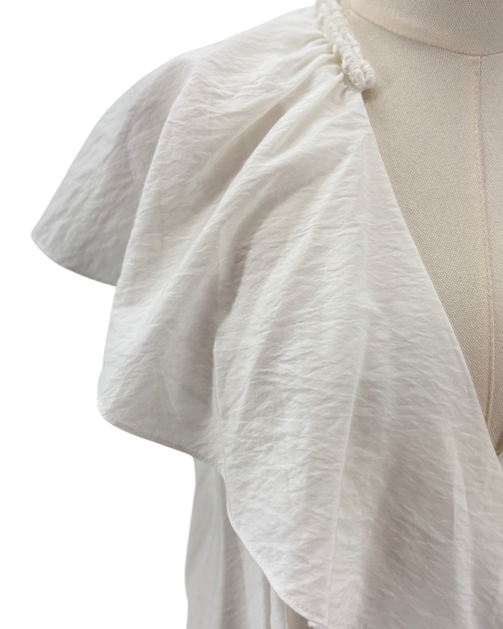 White textured fabric draped over a mannequin on a white background