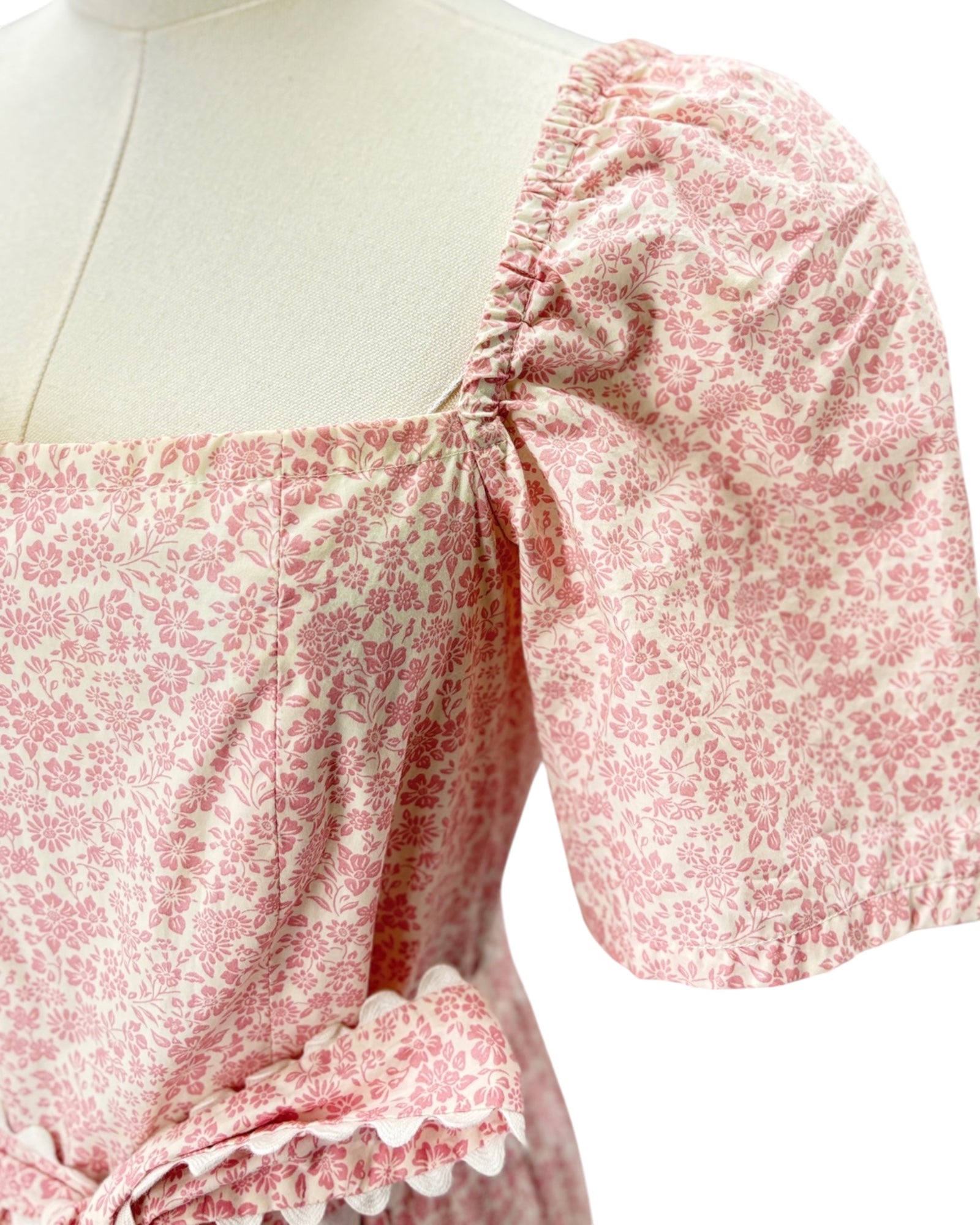 Pink floral dress on a mannequin with a white background