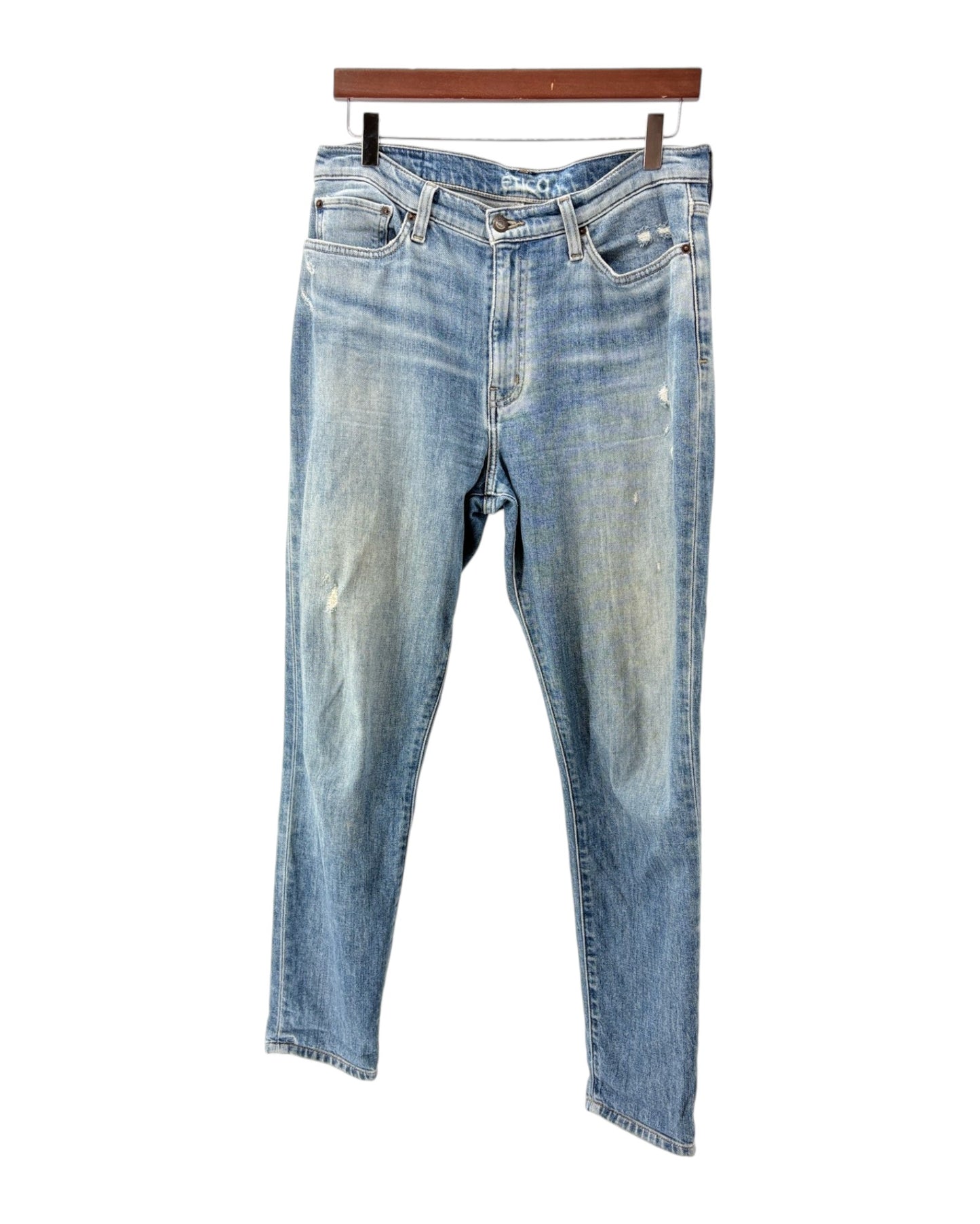 Pair of blue jeans on a hanger against a white background